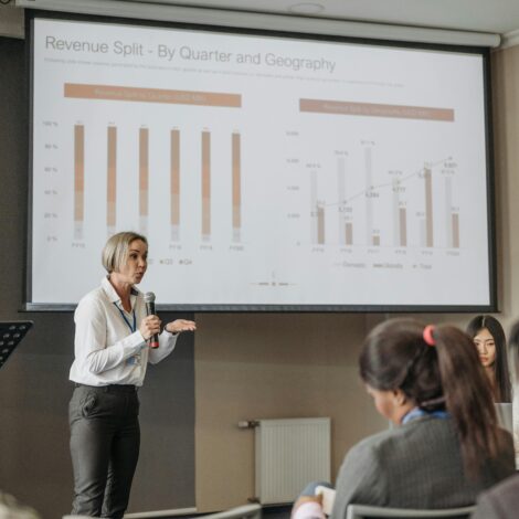 A professional woman leads a seminar on revenue analysis, engaging participants with graphs and data.